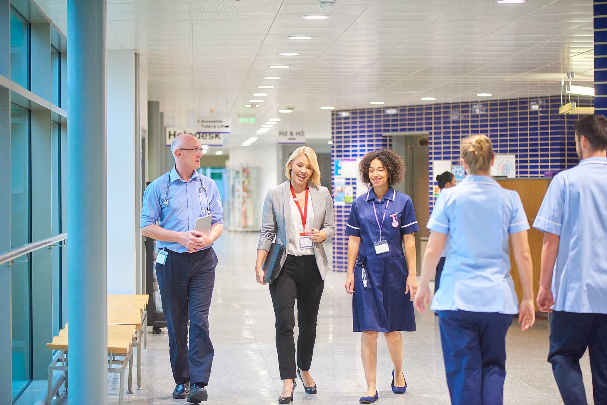 Healthcare leader, clinician and nurse in discussion walking down a ward