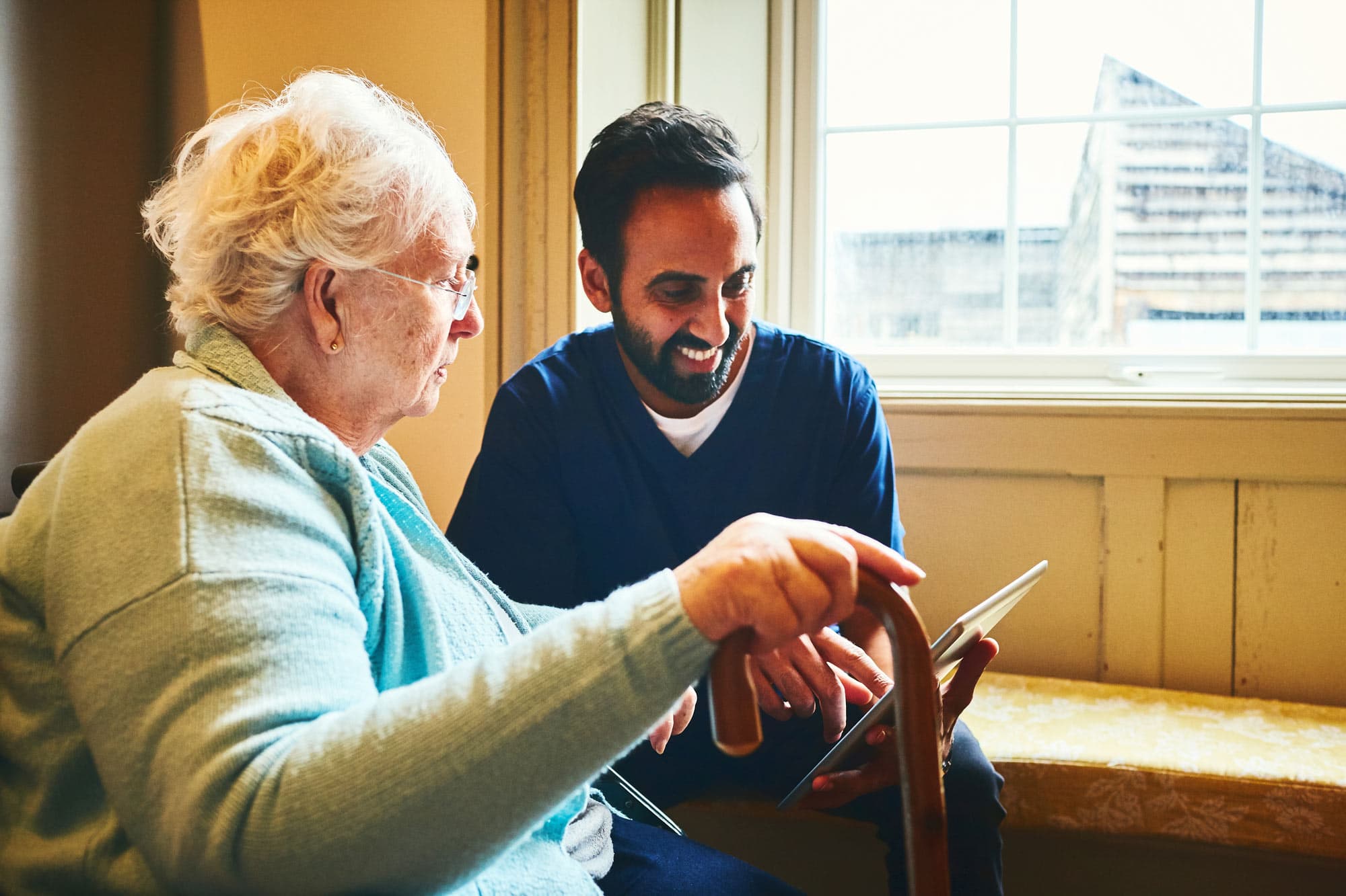 Nurse and patient looking at a tablet screen and smiling